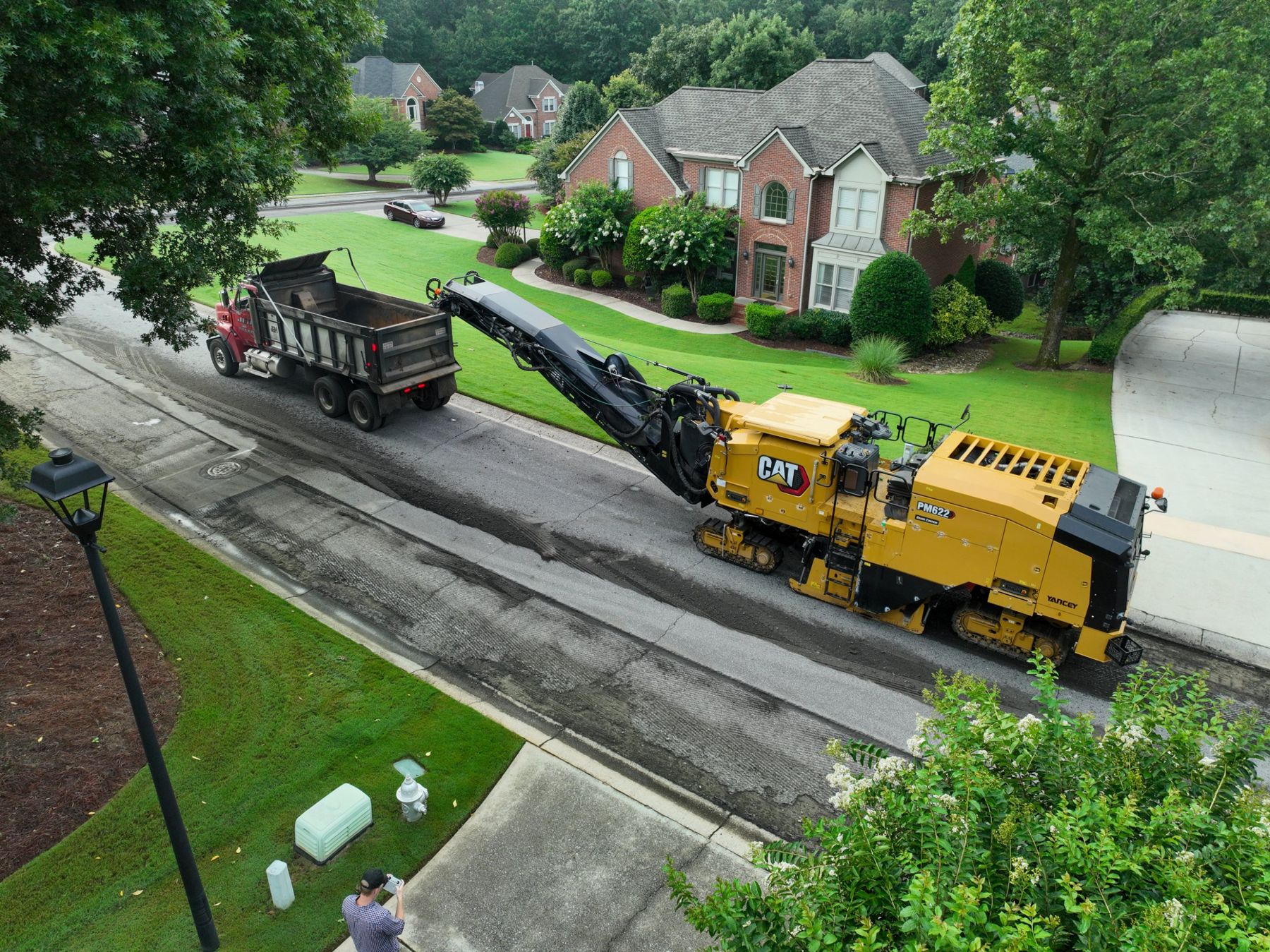 Ian flying a drone beside a milling machine and dump truck
